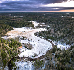 Fototapeta na wymiar Stunning sunrise over valley surrounded with forest and river covered in snow. Scenic aerial landscape.