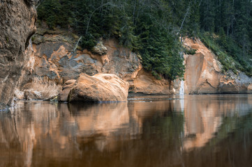 Yellow cliffs next to a calm river with mirror reflection in the water. Long exposure.