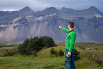 Backside of tall caucasian man wearing green jacket standing in over mountain and fog background. Promoting healthy lifestyle