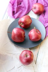 Red fresh apples on a plate, bright cloth on a wooden windowsill, healthy food