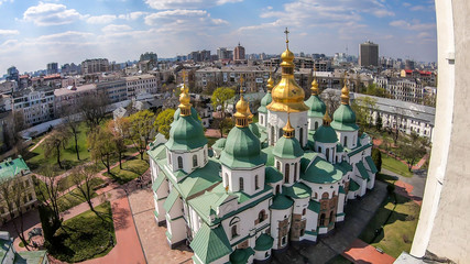 Obraz premium St Sophia's Cathedral in Kiev, Ukraine seen from the bell tower. The cathedral is white with green rooftops and golden turrets. Complex building, consisting of many smaller rooftops and towers.