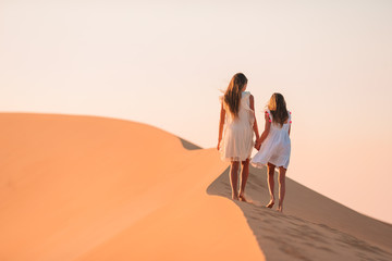 Fototapeta na wymiar Girls among dunes in big desert in Emirates