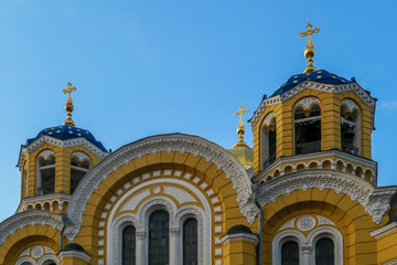 Obraz premium A close-up on the front facade of St Volodymyr's Cathedral, Kiev. The cathedral is painted yellow, with blue and golden-domed rooftop. Very detailed and rich decorations.
