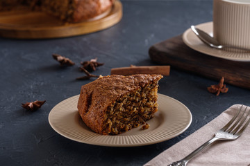 Fragrant and tasty carrot cake with a crispy crust on a plate with a cup of coffee on a dark background