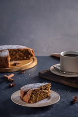 Fragrant and tasty carrot cake with a crispy crust on a plate with a cup of coffee on a dark background