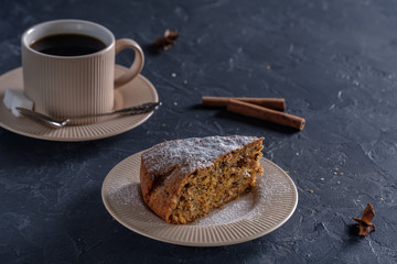 Fragrant and tasty carrot cake with a crispy crust on a plate with a cup of coffee on a dark background
