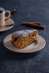 Fragrant and tasty carrot cake with a crispy crust on a plate with a cup of coffee on a dark background