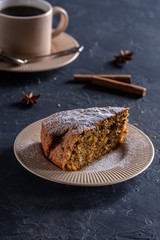 Fragrant and tasty carrot cake with a crispy crust on a plate with a cup of coffee on a dark background