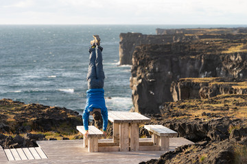 Man keep balance standing on his hands on Sea scape with dangerous vertical cliff background,...