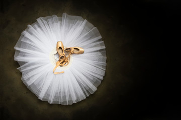 Ballet shoes with ribbons on a white tutu in a dance studio - obrazy, fototapety, plakaty