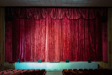 Theater stage with closed red velvet curtains