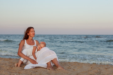 Fototapeta na wymiar Portrait of a beautiful young mother and daughter on the seashore.