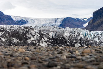 Glacier with ash in the ice with melted water and Icelandic landscape 