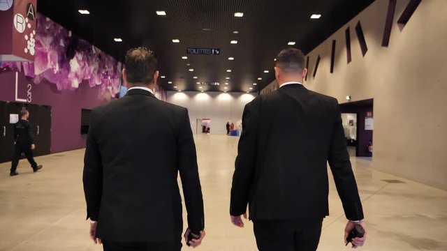 suivi d'agents de s&eacute;curit&eacute; aux cheveux court dans le une grande salle de dos au ralenti