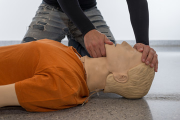 Man teaching cardiopulmonary resuscitation with a dummy on a white background. Front-chin manoeuvre