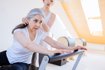 Active senior woman working exercise in the gym. Personal trainer helping senior woman. Workout in gym.