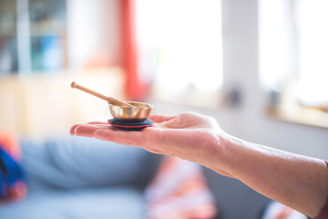 Baby singing bowl: Small metal singing bowl in the hand of a woman. Blurry background.