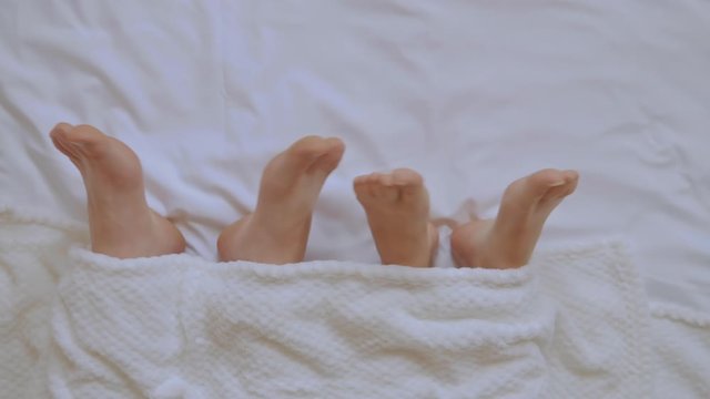 close up woman and man feet in bedroom couple have fun in bed in the morning