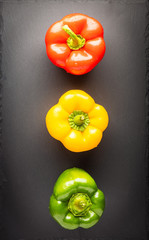 red, yellow and green bell pepper on stone background. Traffic light colors