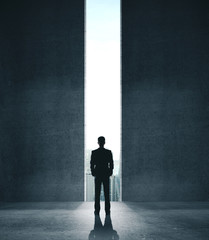 Businessman in concrete room with open door to city
