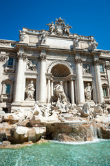 Fototapeta na wymiar Bright sunny view of Trevi Fountain from the waters of the empty pool under blue sky in Rome, Italy