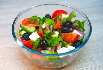Greek salad with tomatoes, cucumbers and feta cheese with olives on the table