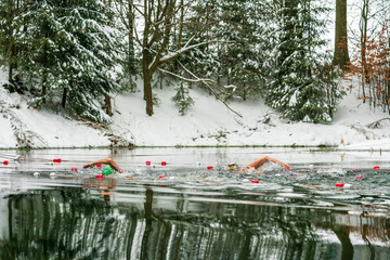 Two extreme athleates swimming in a lake in winter 