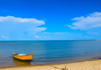 A fishing boat docked at the beach with beautiful blue sea and sky