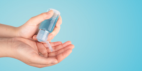 Close up female washing hands with alcohol gel for cleaning sanitize gel pump dispenser on  blue background, health care concept