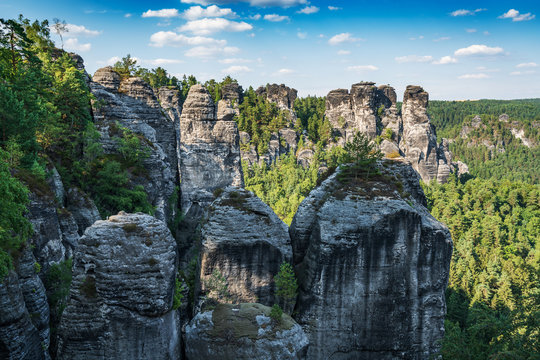 Bad Schandau in Bohemian Switzerland. Bastei bridge and mountain view. Narrow rock, natural sandstone arch in Europe..Hill scenery with greenery, blue sky and sunlight.
