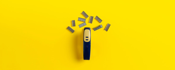 simple stapler and staples isolated on the colorful background in office table wide long banner