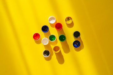 view from above of the colorful paints gouache in pots or cans on the colorful background