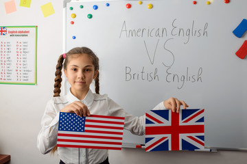 Concept of difference between American English and British English. Young learner showing flags of...