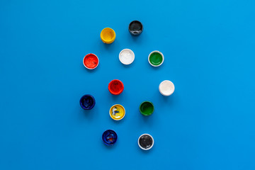 view from above of the colorful paints gouache in pots or cans on the colorful background