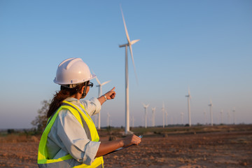 women engineer working and holding the report at wind turbine farm Power Generator Station on...