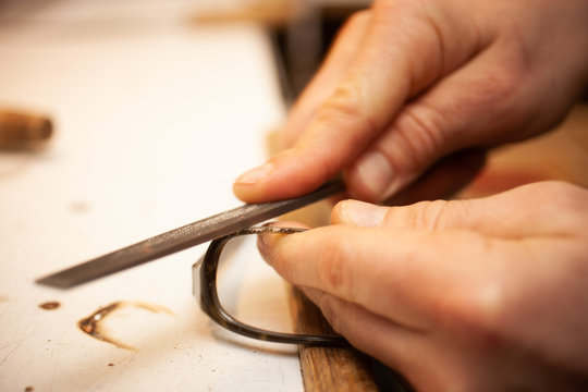 Optiker feilt an einer Brille mit einer Feile