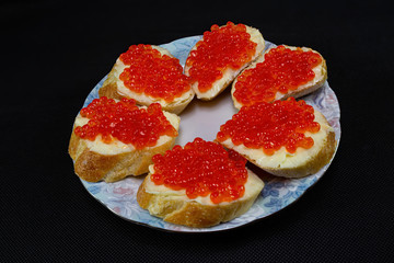 Sandwiches with red caviar on a black background.