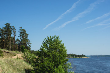 view of the shore of a picturesque river and traces of the plane in the sky