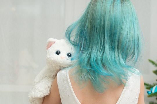 girl with blue hair in a white dress and a toy cat on the background of the New Year tree