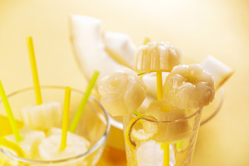 Homemade melon orange fruit sorbet granita popsicles lollies and slices of fresh ripe melon fruit against yellow background. summer dessert, sweet snack. close up