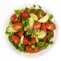 Fresh cucumber salad and cherry tomato in a round white plate on a white background.