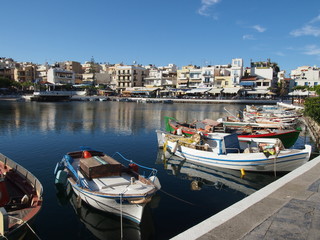 Fototapeta na wymiar A small Mediterranean marina with fishing boats and light colored buildings in the background