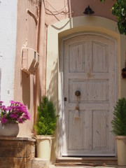 Fototapeta na wymiar Old white door with two potted thuja trees and cream wall paint