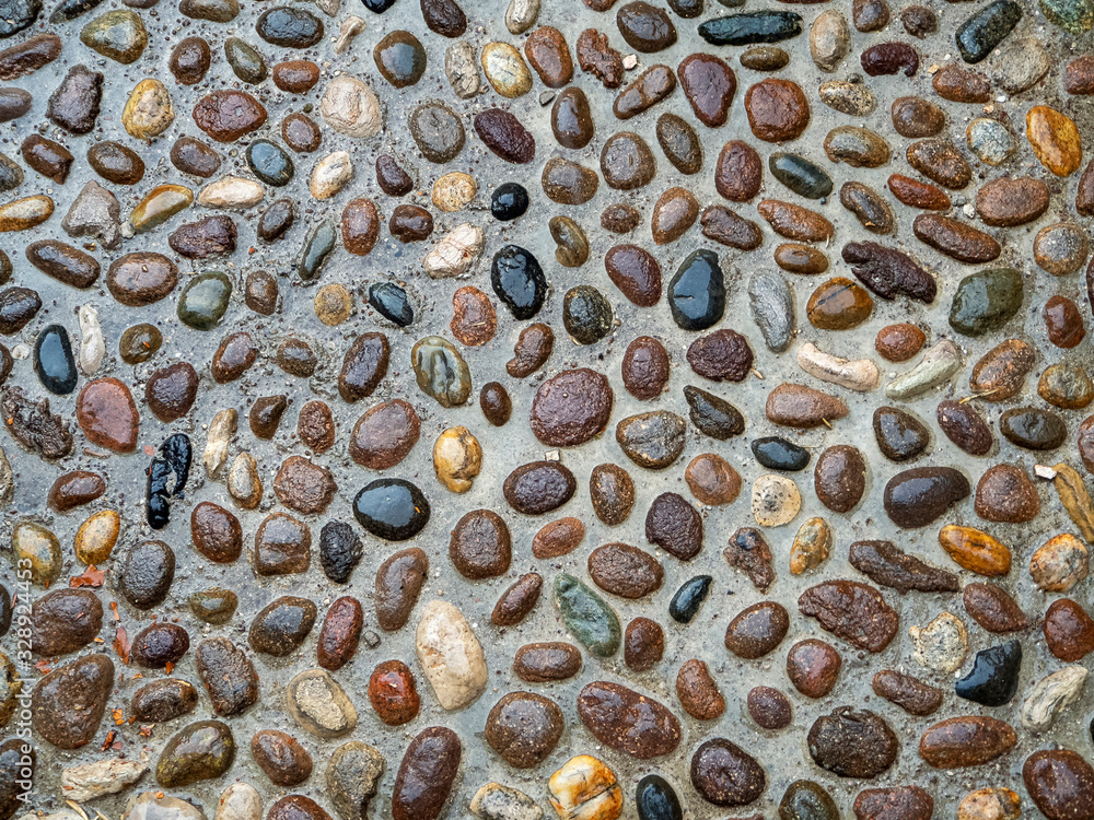 Poster the wet surface of the sidewalk glistens after rain. multi-colored cobblestones make up an abstract 