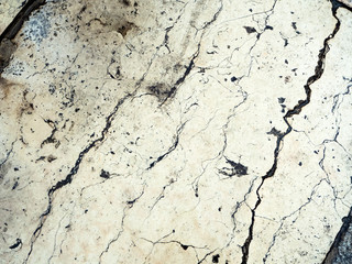 The white old marble slab with cracks is located diagonally. Vintage stone background with a pattern of cracks.
