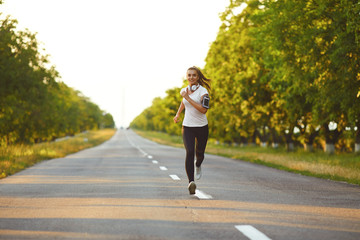 Girl runner runs along the road in summer.
