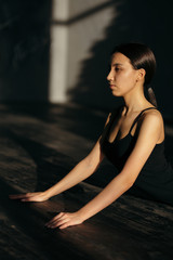 The girl arches her back lying on her stomach. Yoga class in black clothes.