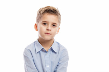 Serious school boy in a blue shirt. Isolated on a white background.