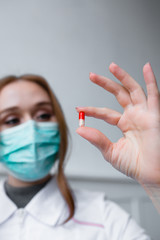 Health safety and medicine concept - beautiful girl doctor holds pill for disease