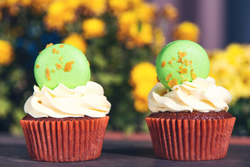 Cupcakes decorated with french macaroons. Delicious Easter cupcakes on table. Easter cupcakes with macaroons.